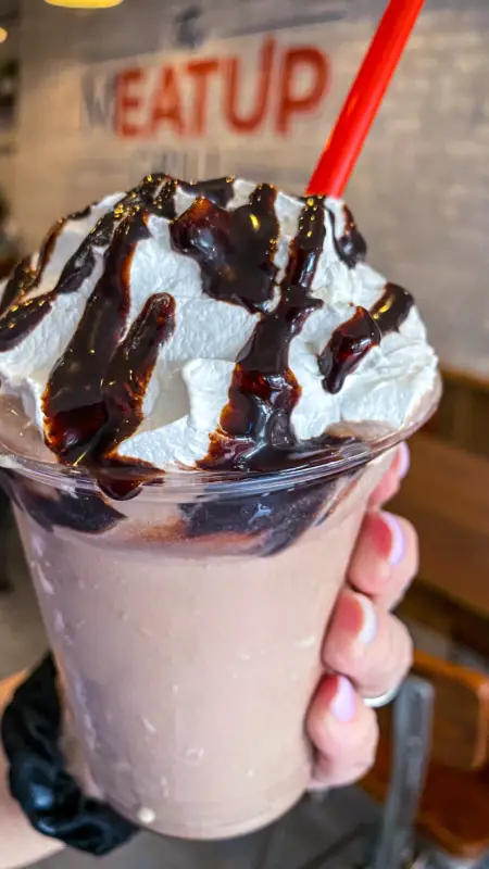 Creamy chocolate milkshake topped with whipped cream and drizzled with chocolate syrup from The Meat Up Grill.