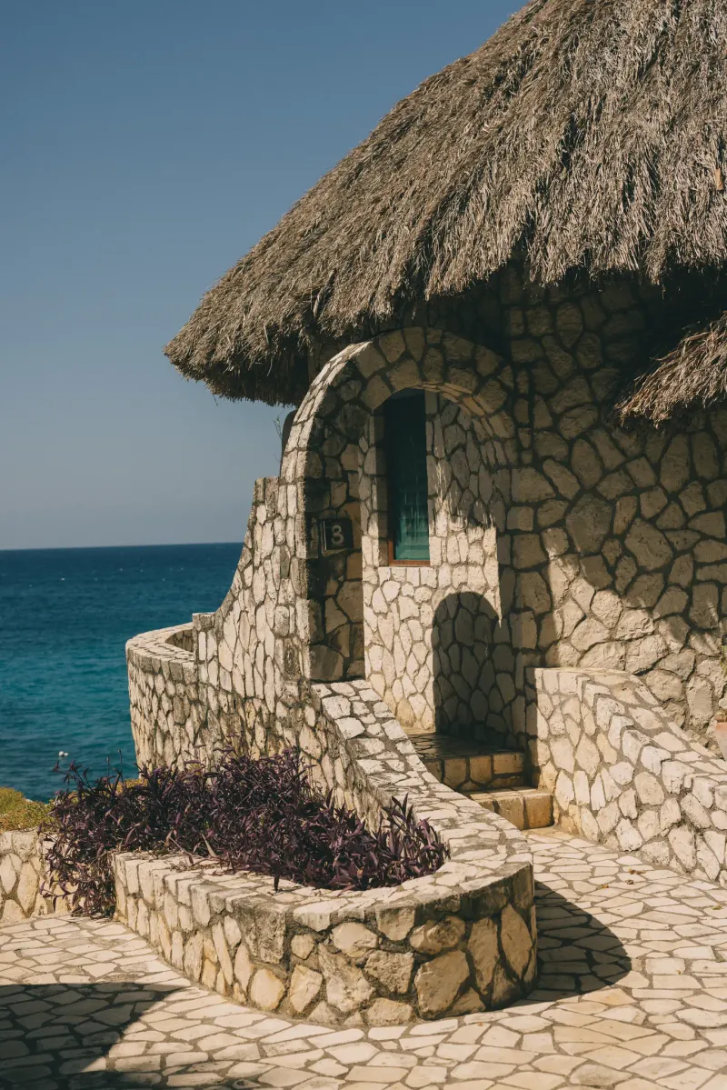 A sculpture of a mermaid sitting on a rock at Xtabi Resort , overlooking the vast Caribbean Sea in Negril, Jamaica, highlighting the unique artistic elements and cliffside setting of the property.