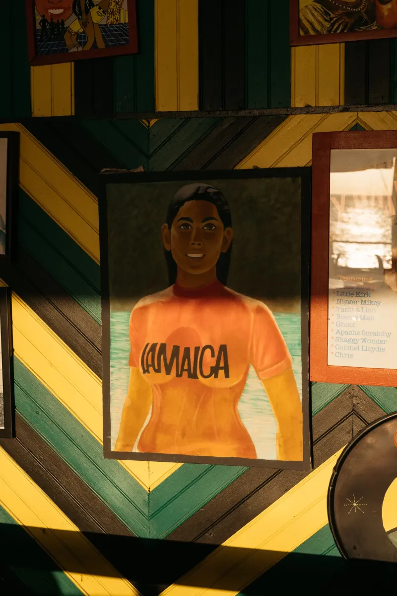 A painting of the famous vintage Jamaican poster of a woman exiting the water in a red shirt with the word Jamaica written on it framed and displayed at the Pushcart Rum Bar and Jerk Center at the Rockhouse Hotel in Negril, Jamaica