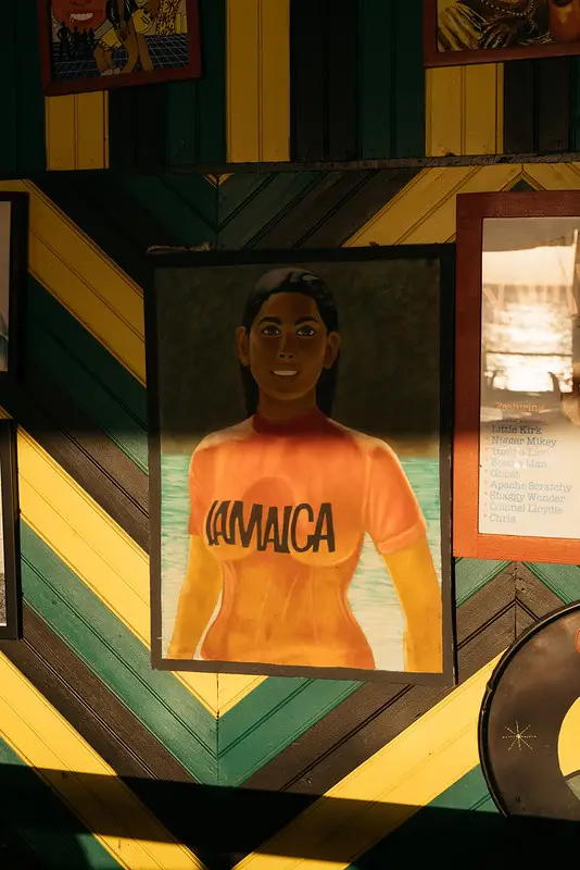 Colorful mural of a woman wearing a 'Jamaica' shirt at Rockhouse Hotel in Negril, Jamaica, set against a vibrant, patterned wall, celebrating local culture and art