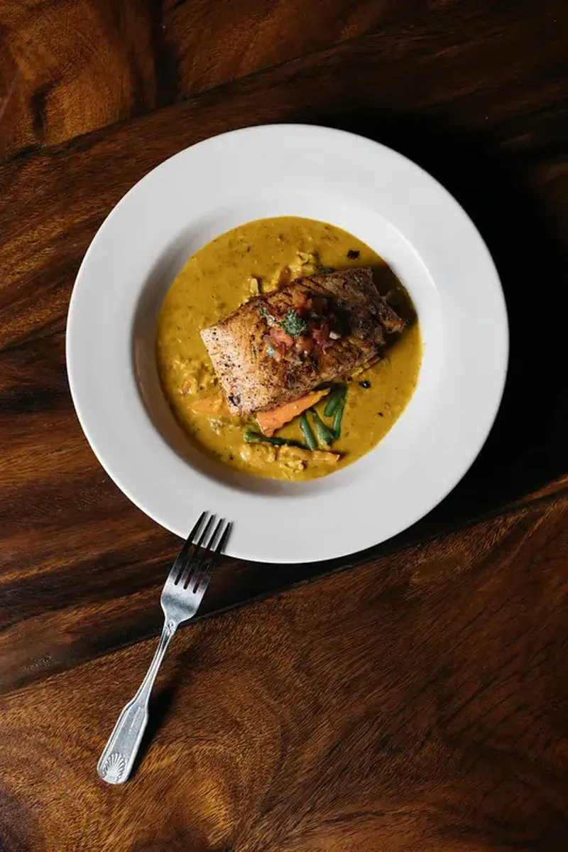 Overhead view of a Snapper Filet in a colorful coconut cream sauce on a bed of fresh vegetables at Rockhouse Restaurant at Rockhouse Hotel in Negril, Jamaica. 