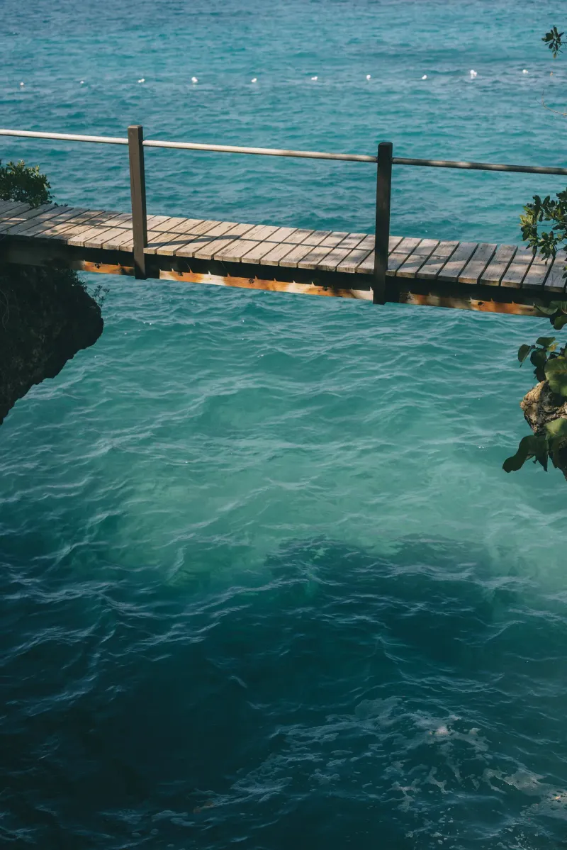 A unique standing on a small pier at Rockhouse Hotel in Negril, Jamaica, with the water and tropical foliage visible, highlighting the resort's serene and picturesque setting.
