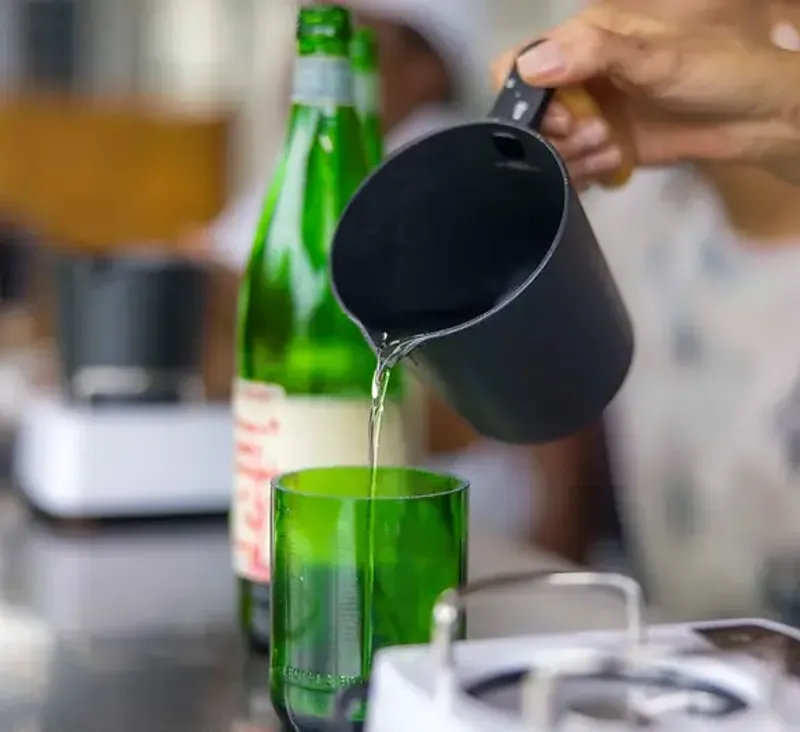 Woman pouring a liquid into a glass, showcasing a wellness activity like juicing or a workshop at Rockhouse Hotel in Negril, Jamaica.