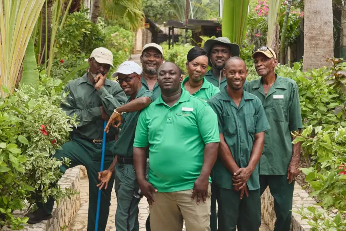 Group of friendly groundskeepers and staff at Rockhouse Hotel in Negril, Jamaica, posing together in the lush gardens—a showcase of the hotel's welcoming team.