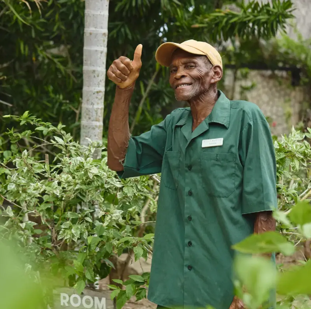 Smiling man at Rockhouse Hotel in Negril, Jamaica, giving a thumbs-up in the tropical gardens—a happy and welcoming staff member.
