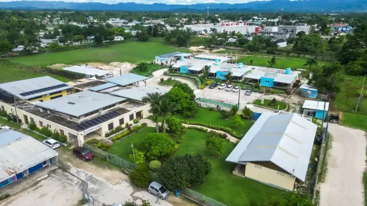 A student and a teacher from the Rockhouse Foundation school in Negril, Jamaica, engaging in a learning activity with a puzzle board in a brightly lit classroom—a heartwarming moment of education and interaction.