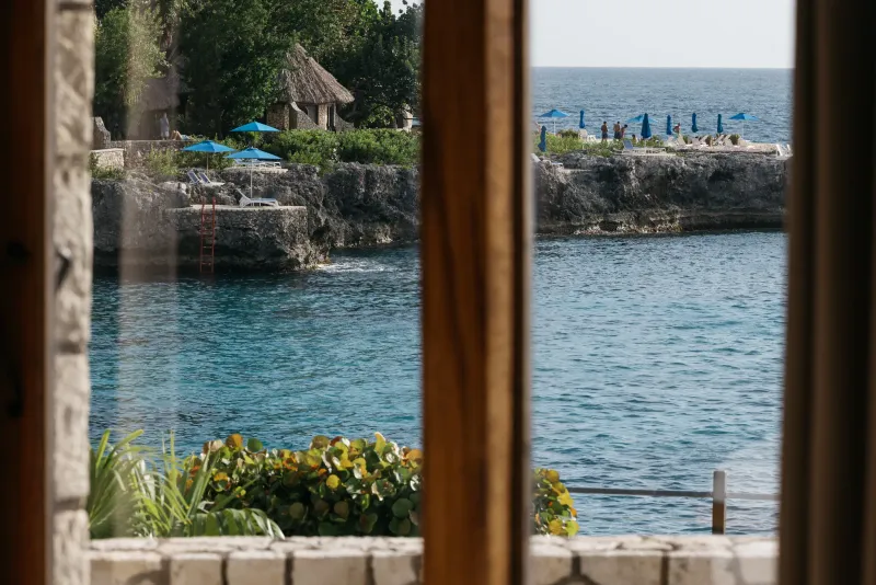 A split-image view from Rockhouse Hotel in Negril, Jamaica, showing two windows framing the breathtaking sea and island views, highlighting the resort's unique perspective and incredible scenery.