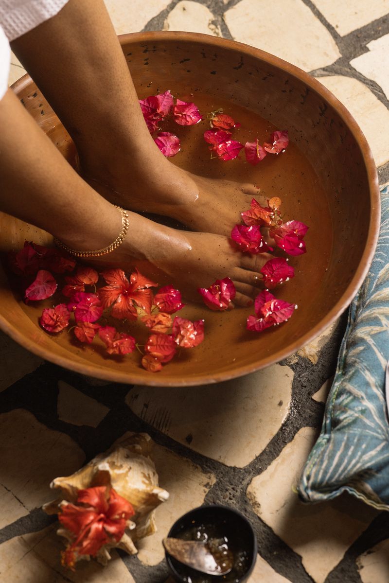 Close-up of feet soaking in water, petals and essential oils from a person receiving a signature foot soak and welcome ceremony at the Rockhouse Spa at the Rockhouse Hotel in Negril, Jamaica