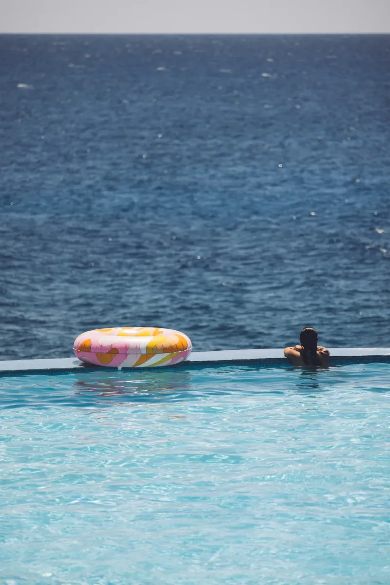 A pool float and a woman at the infinity edge of the Rockhouse hotel infinity pool overlooking the Caribbean sea