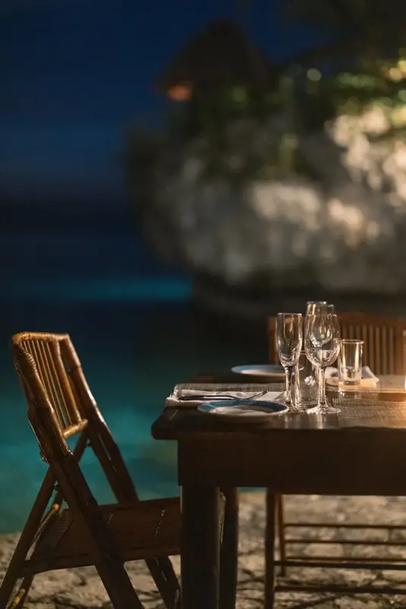 A view from a cliffside dining table elegantly set on the water on Vincent's Deck at Rockhouse Restaurant nightstand showcasing the unique, natural beauty of dining at Rockhouse Hotel in Negril, Jamaica.