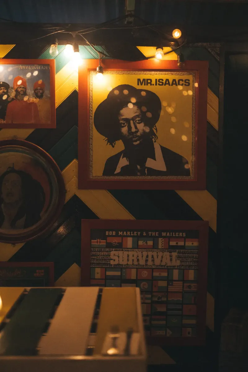 A vibrant wall display at Rockhouse Hotel in Negril, Jamaica, featuring framed posters of Jamaican icons like Bob Marley and Mr. Isaacs, highlighting the resort's celebration of local culture and music.