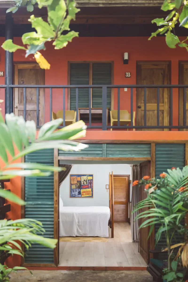 The inviting red-painted facade of a cabin at Rockhouse Hotel in Negril, Jamaica, with a staircase leading up to a private entrance, highlighting the resort's colorful and unique lodging.
