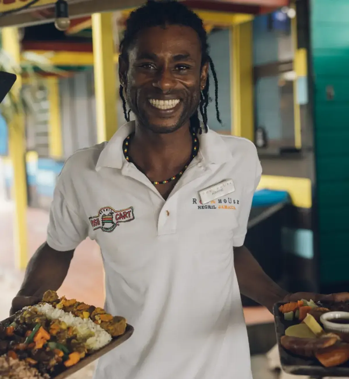 Friendly staff member at Rockhouse Hotel’s Pushcart Restaurant in Negril, Jamaica, welcoming guests with a warm smile and authentic island hospitality.