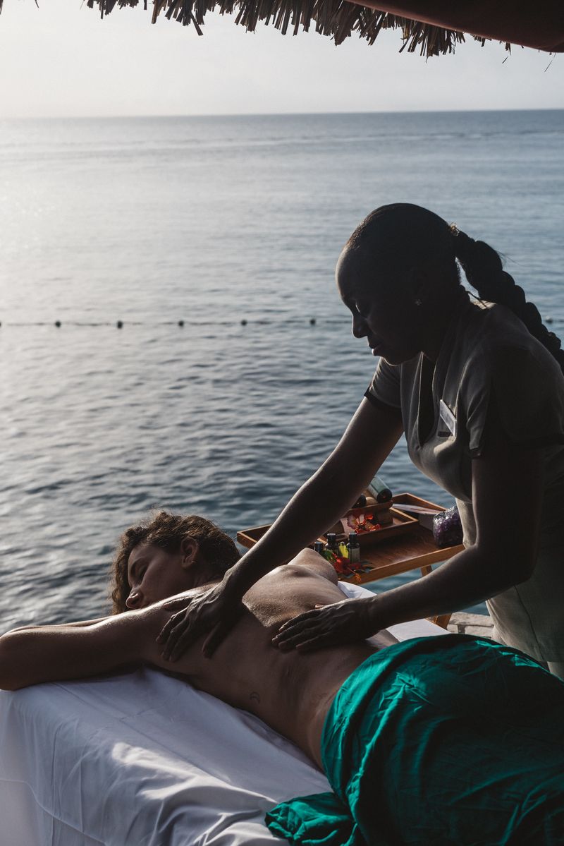 Person receiving a signature massage in a cabana overlooking the sea by a trained spa therapist, highlighting a spa treatment available at the Rockhouse Hotel in Negril, Jamaica