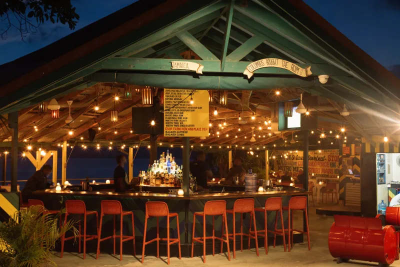 A lively bar area at Rockhouse Hotel in Negril, Jamaica, with a welcoming vibe created by warm lighting and a cozy setup, showcasing the resort's social and recreational spaces.