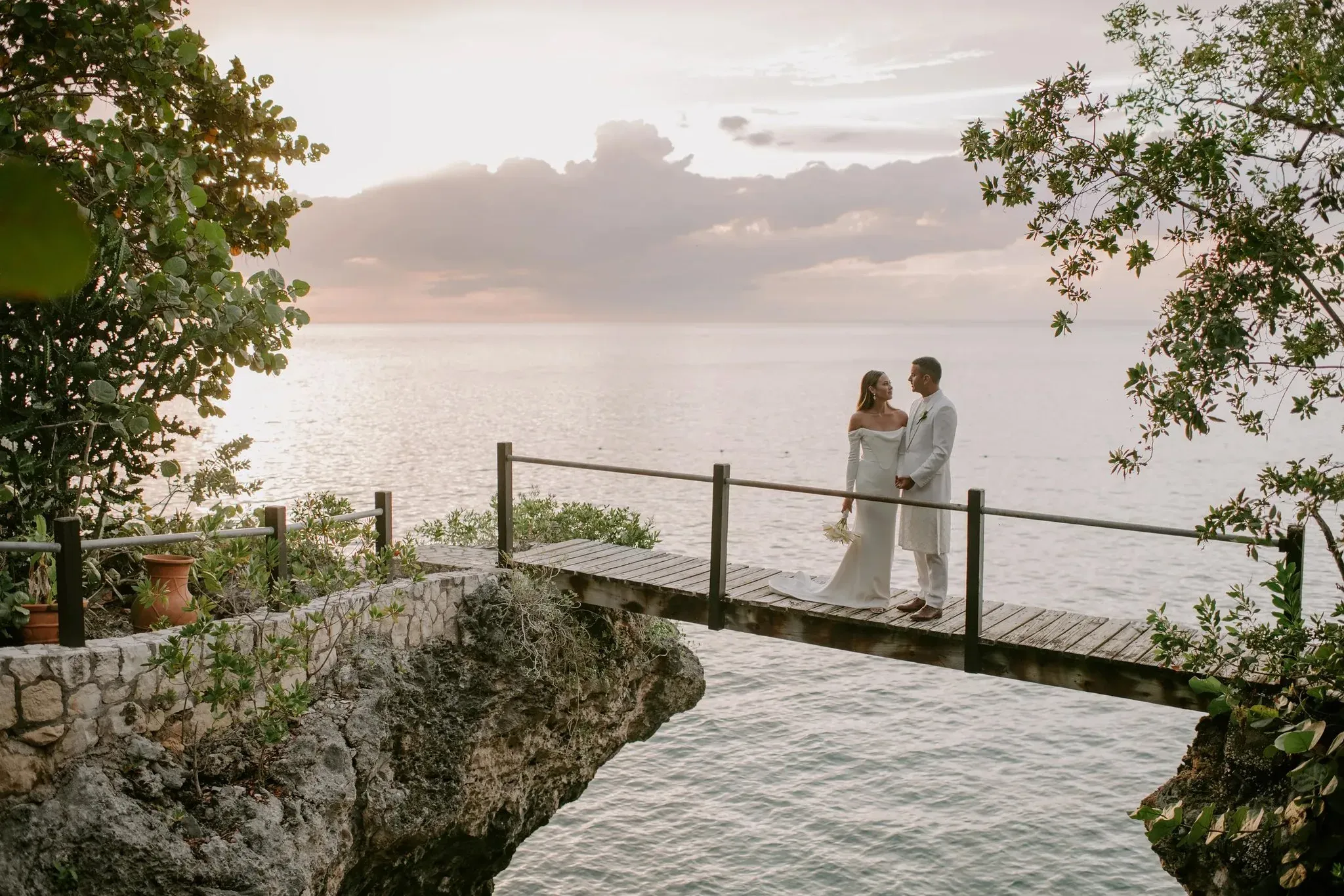 Newlyweds walking hand in hand through the lush tropical gardens at Rockhouse Hotel in Negril, Jamaica, surrounded by dense greenery as they share a joyful, intimate moment on their wedding day.