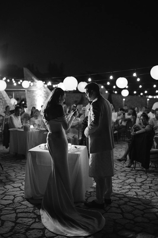 Black and white image of a bride and groom standing by a small table under string lights at a wedding reception at Rockhouse Hotel in Negril, Jamaica, highlighting a romantic wedding venue at Rockhouse Hotel.