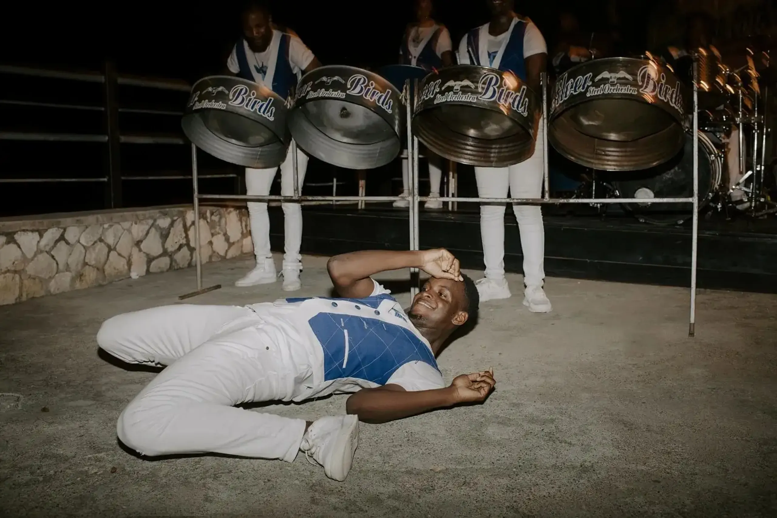 Steel pan band member smiling and lying on the ground during a performance at Rockhouse Hotel in Negril, Jamaica, highlighting a lively entertainment experience at Rockhouse Hotel.