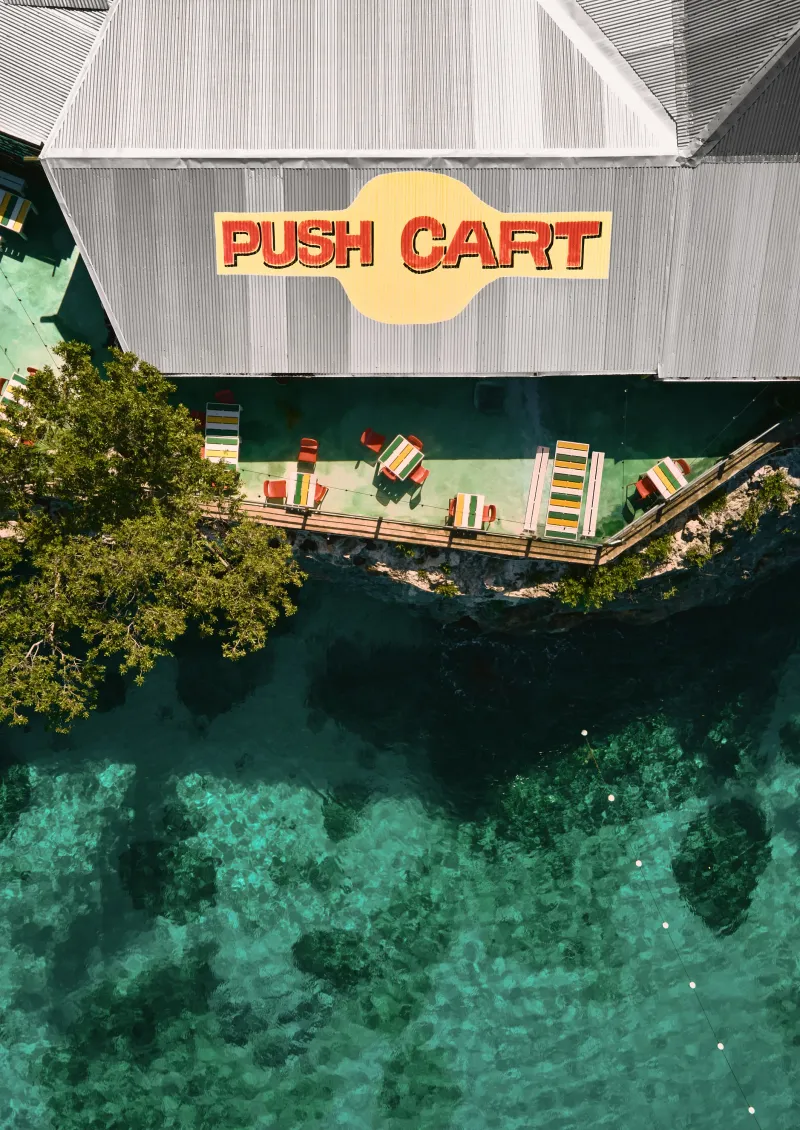 An aerial view of Pushcart Jerk Center and Rum Bar showing it's location overlooking the ocean with a view of the cliffside dining terrace