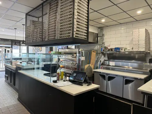 Inside view of Crustinos Pizza kitchen, highlighting their authentic pizza-making process.