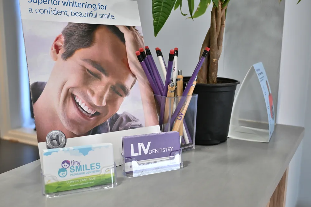 Reception desk with Liv Dentistry business cards, pens, and a plant - Liv Dentistry  