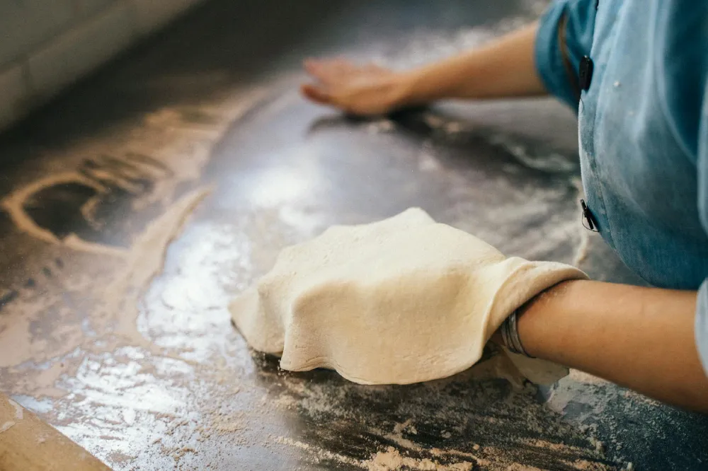 A chef at Crustinos Pizza expertly hand-tossing dough, highlighting the traditional techniques and craftsmanship behind their authentic New York-style pizzas.