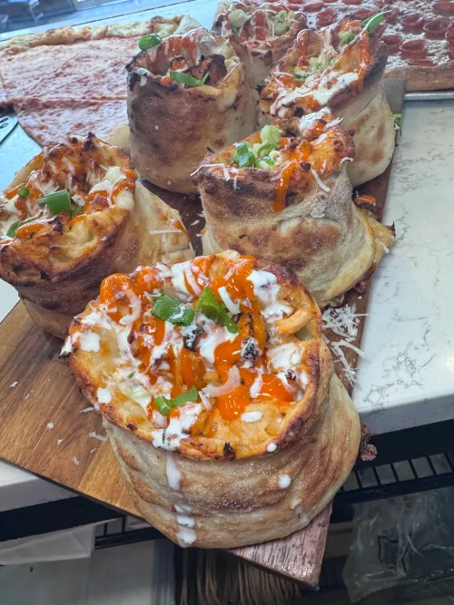 Freshly baked focaccia and pizza rolls at Crustinos Pizza, topped with veggies and cheese.