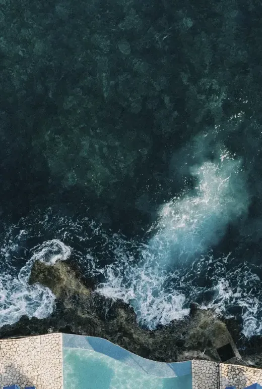 Aerial view of Rockhouse Hotel’s cliffside sun decks and turquoise Caribbean Sea in Negril, Jamaica, highlighting luxury resort amenities and natural beauty
