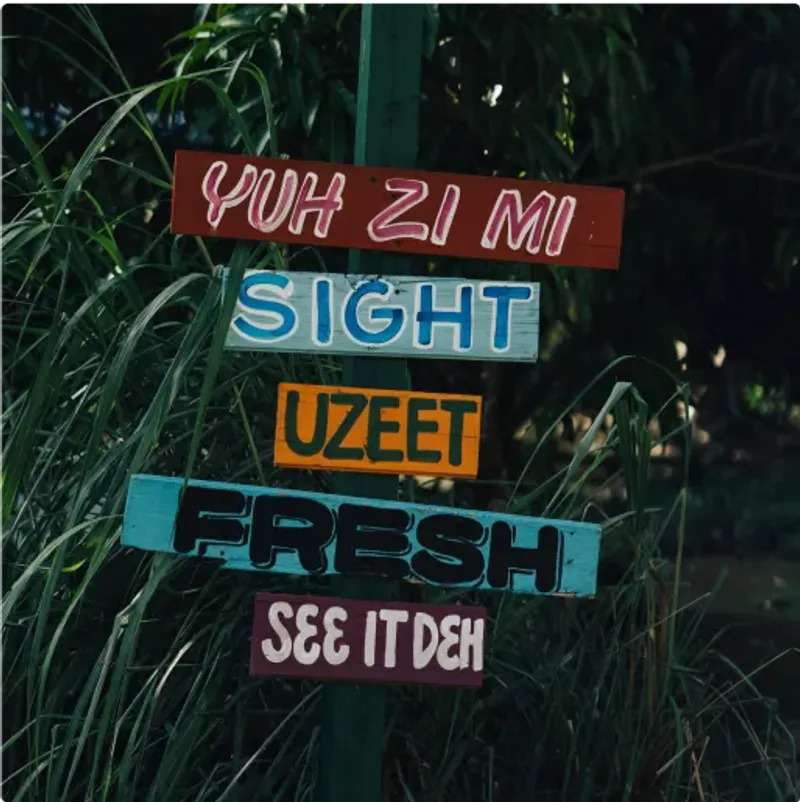 Colorful Jamaican patois signs reading “Yuh Zi Mi,” “Sight,” “UZeet,” “Fresh,” and “See It Deh,” displayed along a lush garden path at Rockhouse Hotel in Negril, Jamaica.