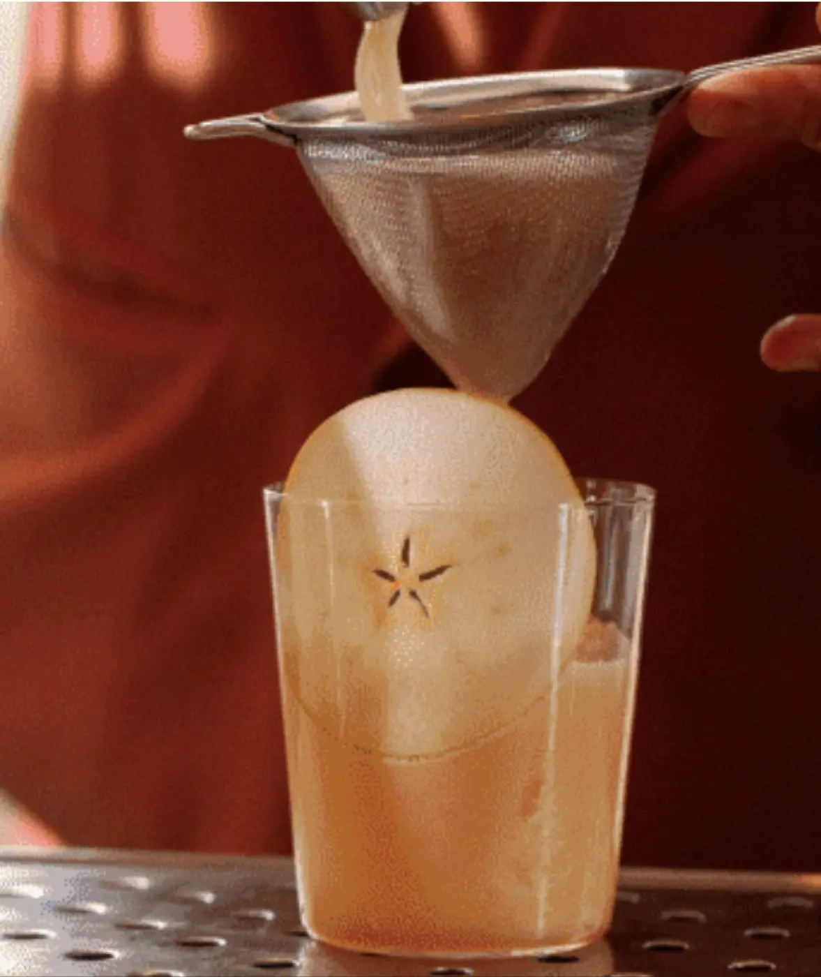 A cocktail being fine-strained at Overstory