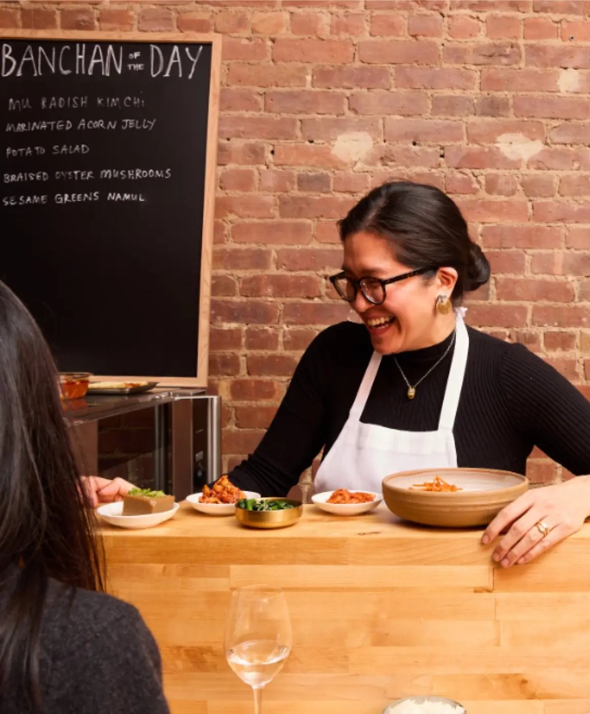 Chef Sunny Lee serving banchan at the counter at Sunn's